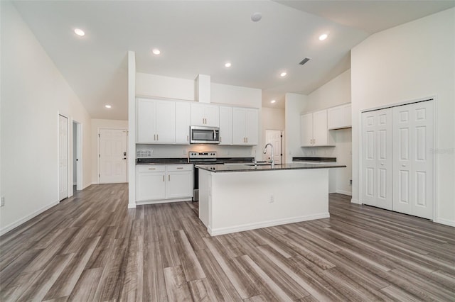 kitchen with light hardwood / wood-style flooring, white cabinetry, a kitchen island with sink, and stainless steel appliances