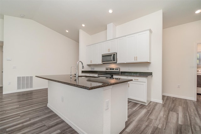 kitchen with an island with sink, stainless steel appliances, and white cabinetry