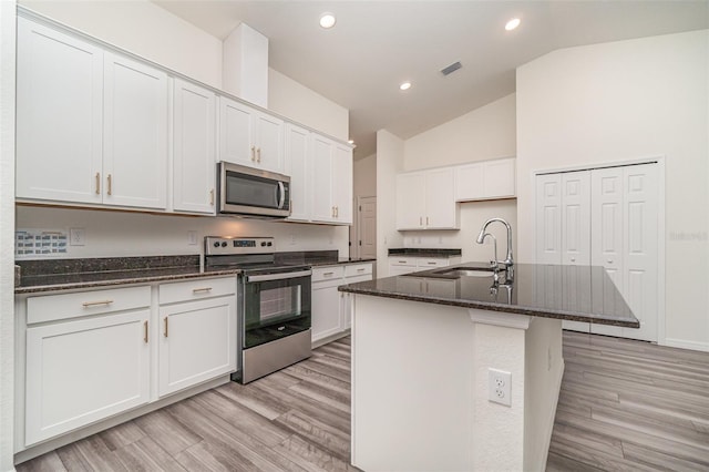 kitchen with white cabinetry, light wood-type flooring, appliances with stainless steel finishes, and an island with sink