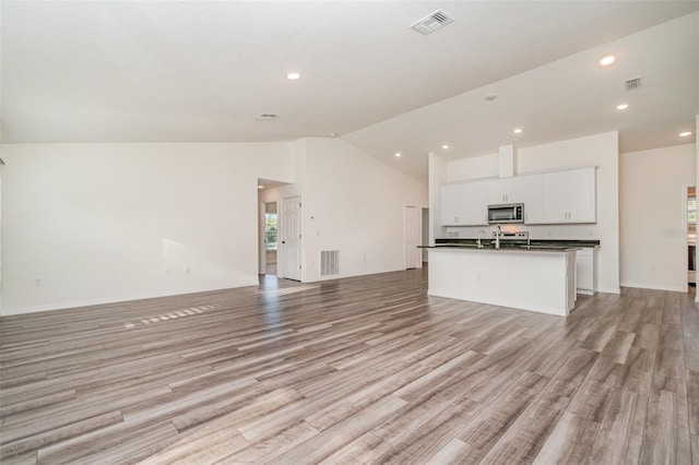 unfurnished living room with light hardwood / wood-style floors, high vaulted ceiling, and sink