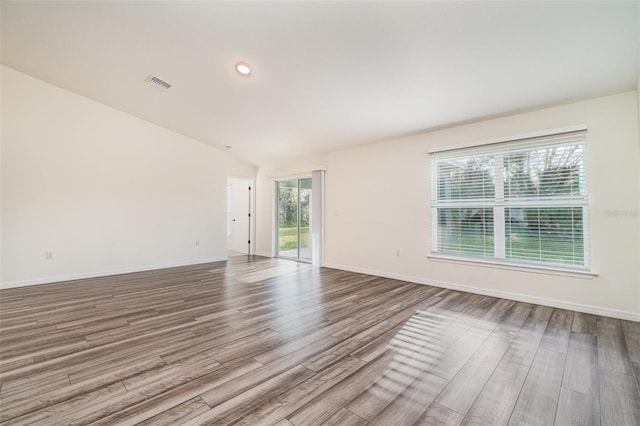 unfurnished room with hardwood / wood-style flooring and lofted ceiling