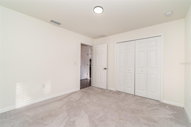 unfurnished bedroom featuring a closet and light colored carpet