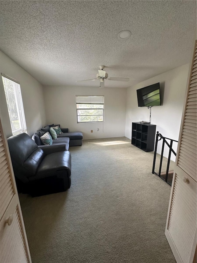 living room with ceiling fan, carpet, and a textured ceiling