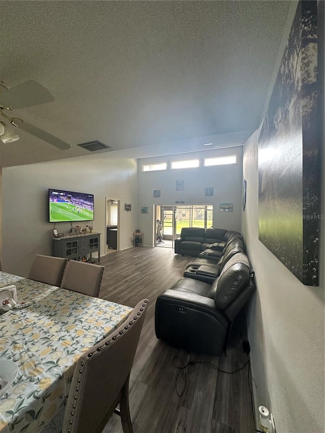 living room featuring ceiling fan, wood-type flooring, and a textured ceiling