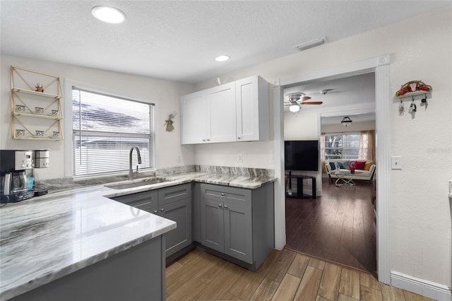 kitchen featuring sink, hardwood / wood-style floors, gray cabinets, white cabinets, and a textured ceiling