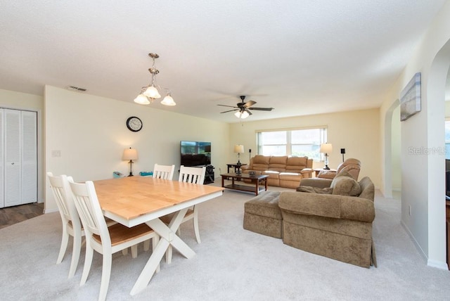 dining area with light colored carpet and ceiling fan with notable chandelier