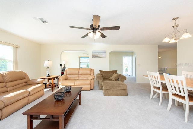 living room featuring light carpet and ceiling fan with notable chandelier