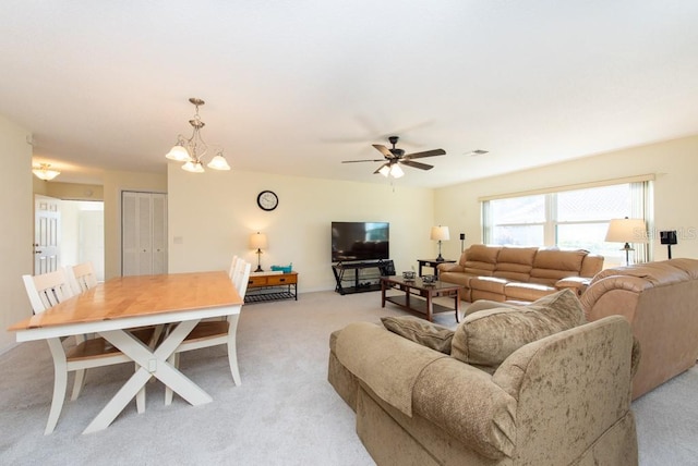 living room featuring light carpet and ceiling fan with notable chandelier