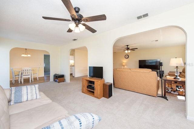 living room with light carpet and ceiling fan with notable chandelier