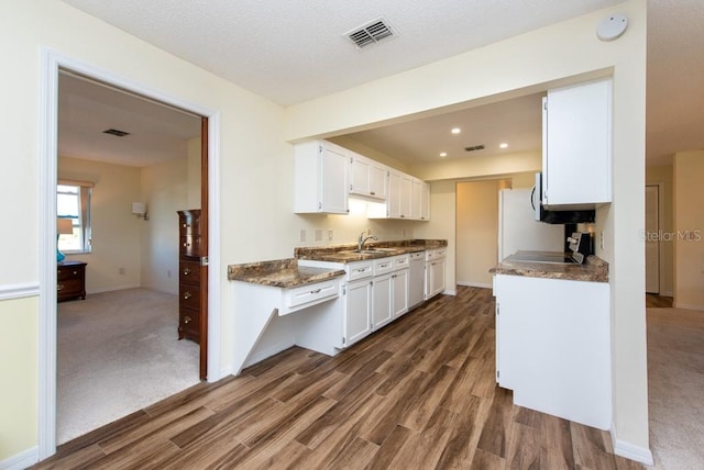 kitchen with dishwasher, dark stone countertops, sink, white cabinets, and dark hardwood / wood-style flooring