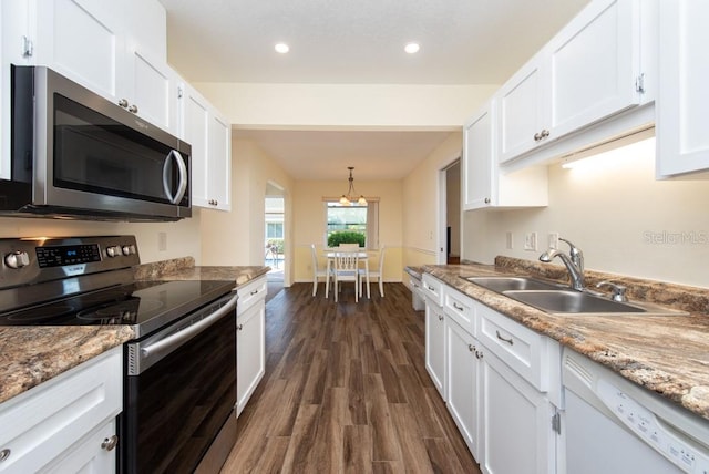 kitchen featuring appliances with stainless steel finishes, sink, hanging light fixtures, white cabinetry, and dark wood-type flooring