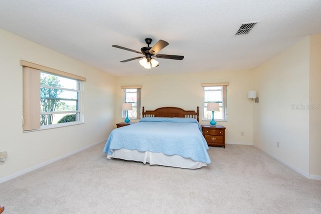 carpeted bedroom featuring multiple windows and ceiling fan