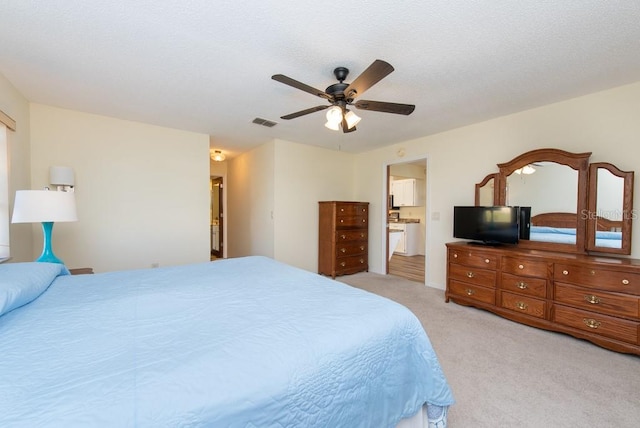 carpeted bedroom with ensuite bath and ceiling fan