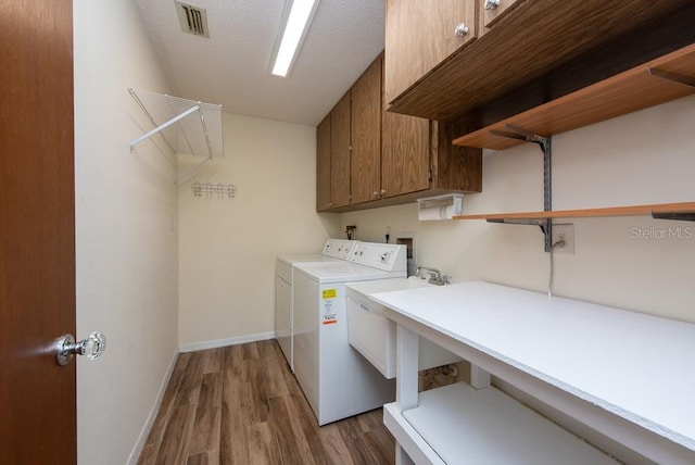 clothes washing area featuring cabinets, a textured ceiling, dark wood-type flooring, and washing machine and dryer