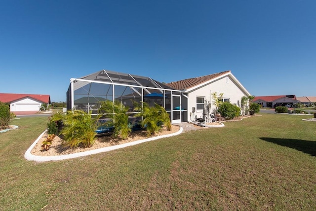 rear view of house featuring a yard, a garage, and glass enclosure