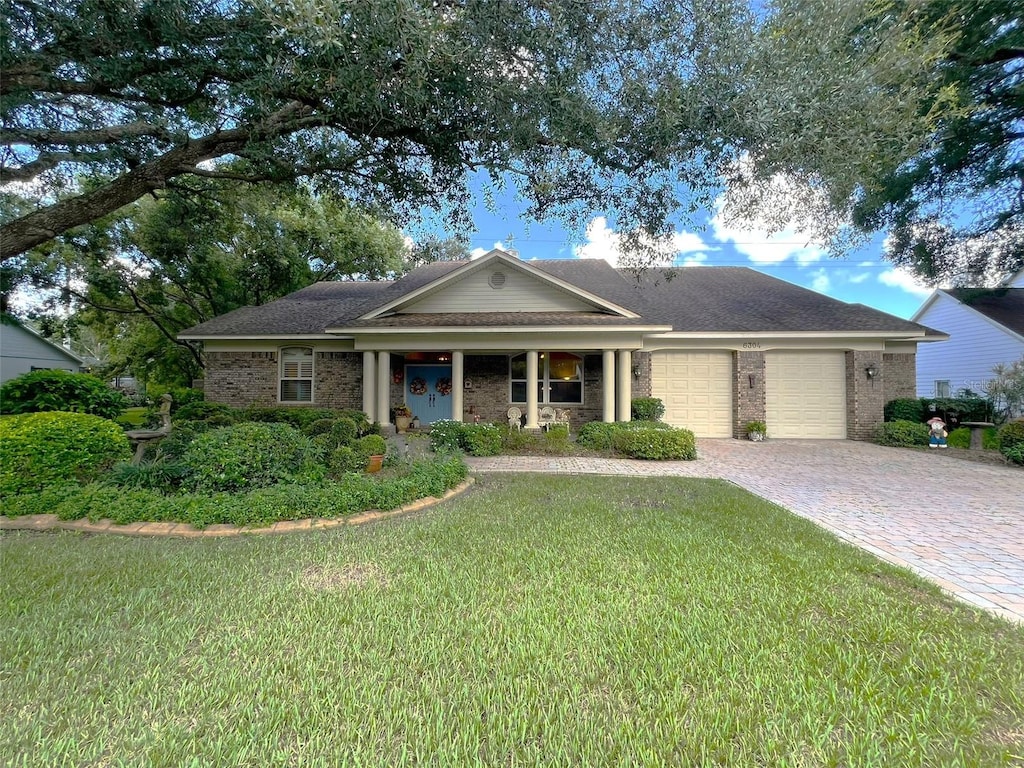 single story home with a garage, a front lawn, and a porch