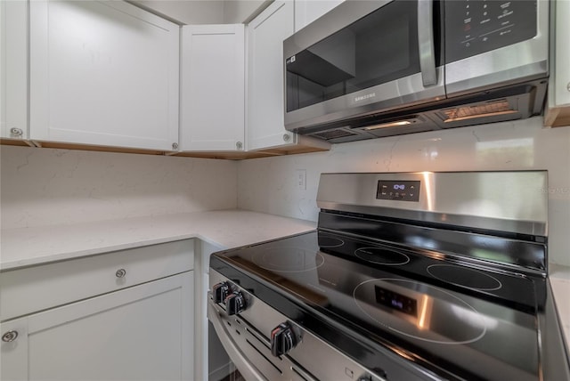 1328 Barry St, Clearwater, FL 33756 - kitchen with stainless steel appliances, decorative backsplash, and white cabinetry