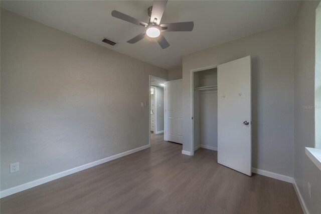 1328 Barry St, Clearwater, FL 33756 - unfurnished bedroom with wood finished floors, a closet, baseboards, and a ceiling fan
