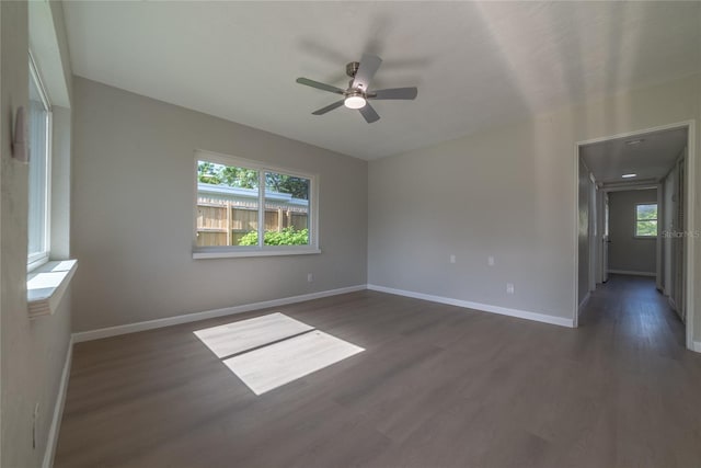 unfurnished room featuring ceiling fan, a healthy amount of sunlight, and dark wood-type flooring