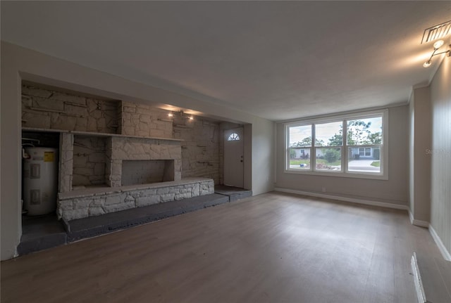 unfurnished living room featuring water heater, a fireplace, and hardwood / wood-style flooring