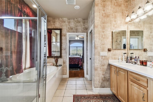 bathroom featuring vanity, a relaxing tiled tub, ceiling fan, and tile patterned flooring