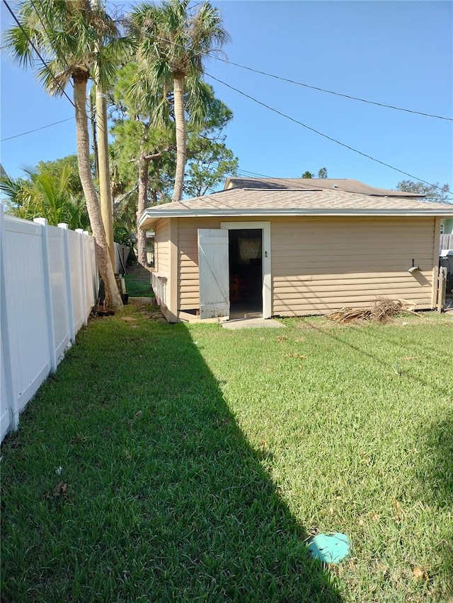 rear view of house featuring a storage unit and a lawn