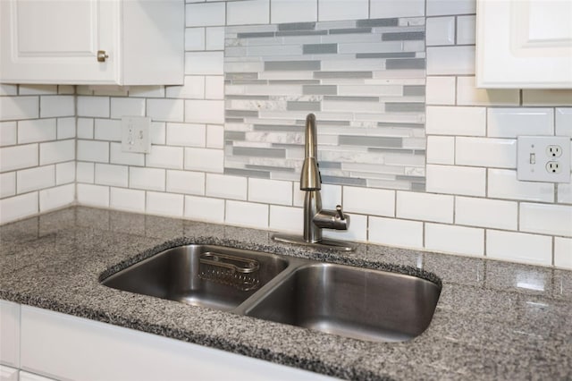 details with white cabinetry, decorative backsplash, sink, and dark stone counters