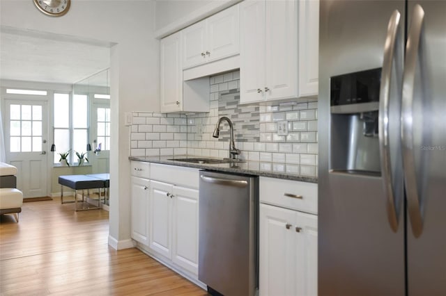 kitchen with white cabinetry, light hardwood / wood-style flooring, stainless steel appliances, and dark stone countertops