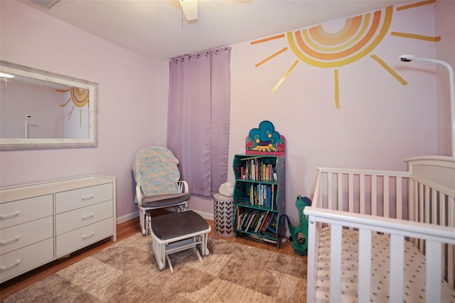 bedroom with ceiling fan, light hardwood / wood-style floors, and a nursery area