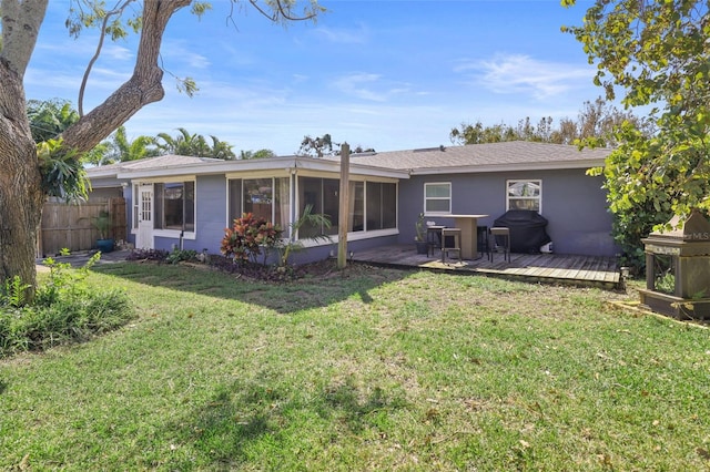 back of property featuring a wooden deck, a yard, and a sunroom