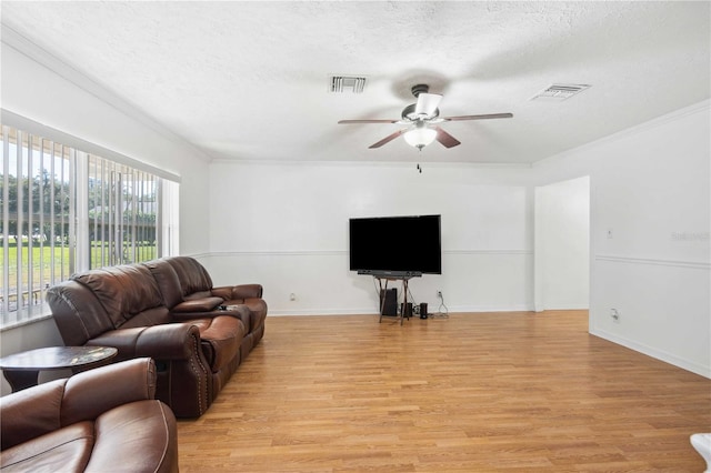 living room featuring ceiling fan, a textured ceiling, light hardwood / wood-style floors, and crown molding