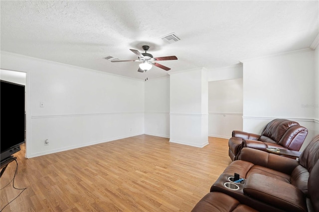 living room with ceiling fan, a textured ceiling, light wood-type flooring, and crown molding