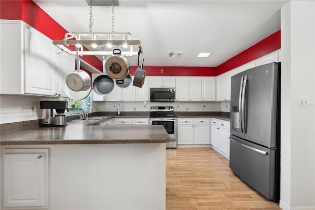 kitchen with white cabinetry, appliances with stainless steel finishes, backsplash, light hardwood / wood-style floors, and kitchen peninsula