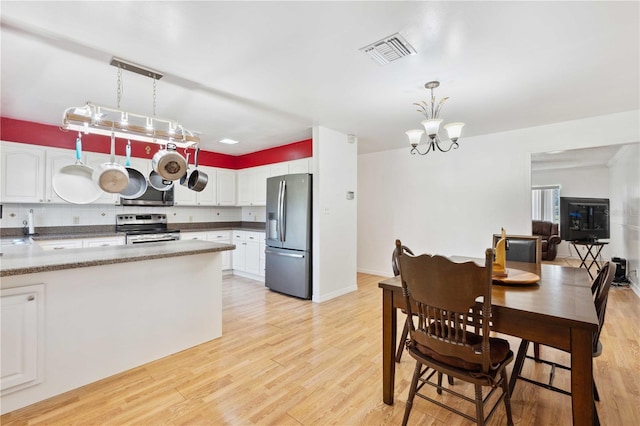 kitchen with white cabinetry, light wood-type flooring, stainless steel appliances, and decorative light fixtures