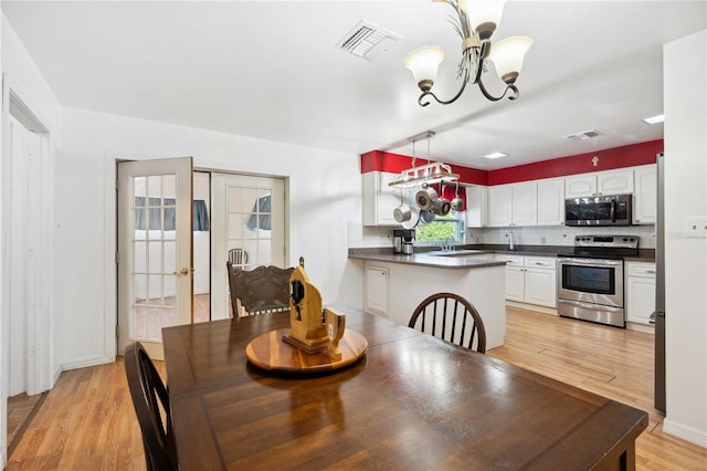 dining room with sink, a notable chandelier, and light hardwood / wood-style flooring