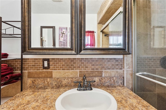 bathroom with vanity, an enclosed shower, and a textured ceiling