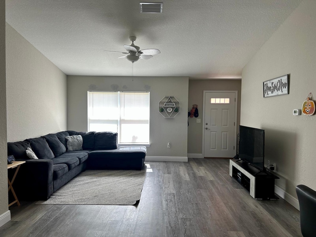 living room featuring a textured ceiling, hardwood / wood-style flooring, and ceiling fan