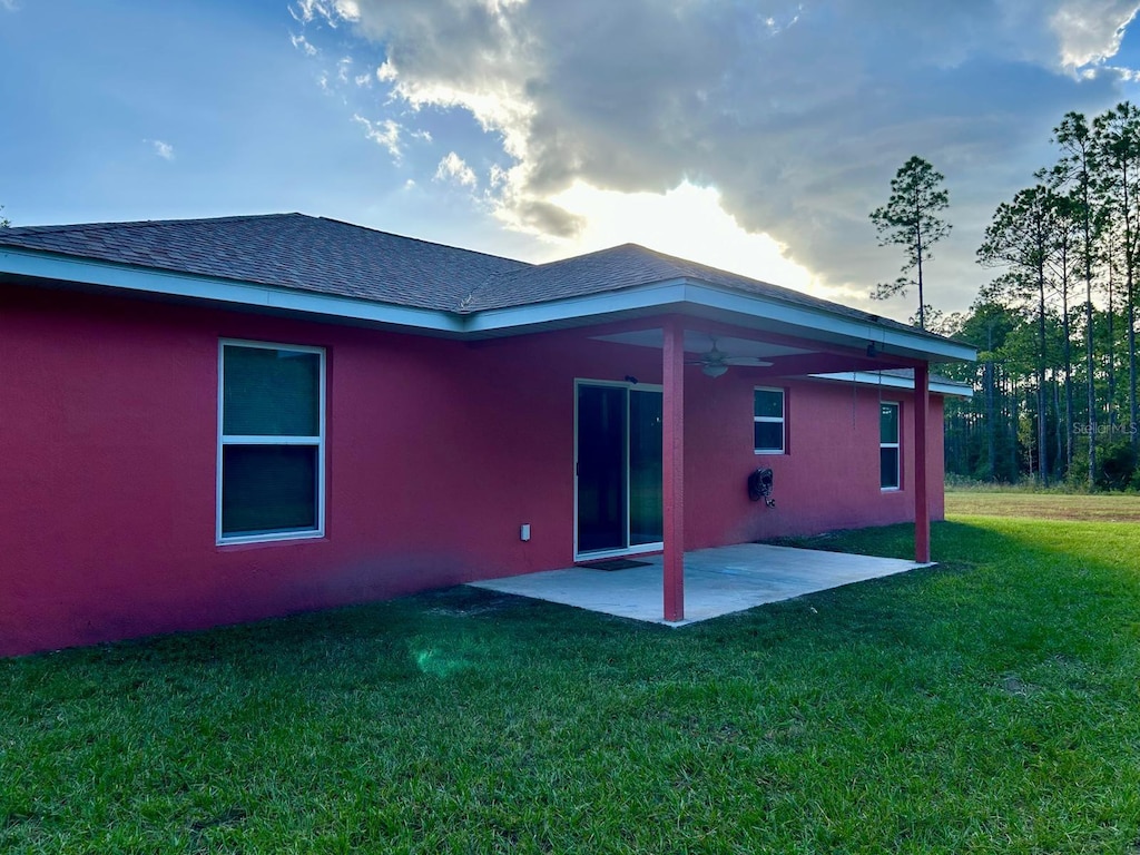 rear view of property featuring a yard, a patio, and ceiling fan