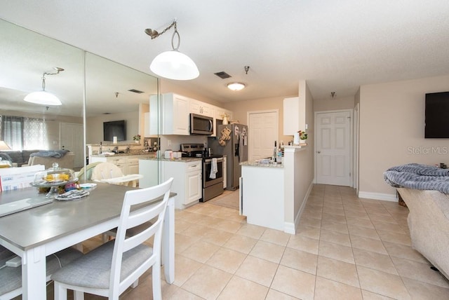 kitchen with kitchen peninsula, white cabinetry, stainless steel appliances, pendant lighting, and light tile patterned floors