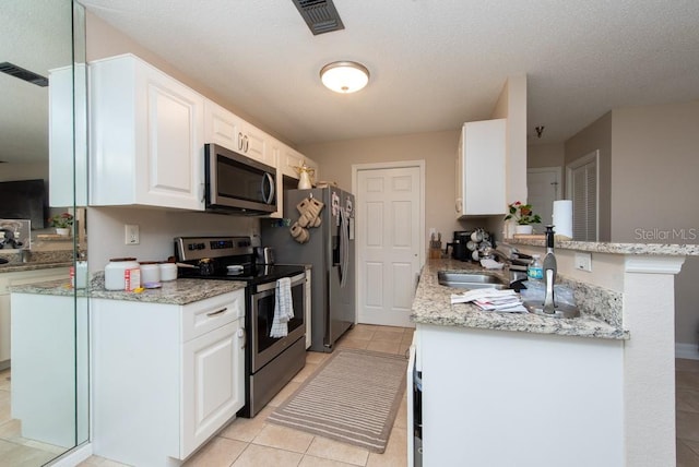 kitchen with kitchen peninsula, stainless steel appliances, sink, light stone countertops, and white cabinets