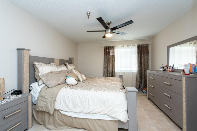 bedroom featuring ceiling fan, a textured ceiling, multiple windows, and light tile patterned floors