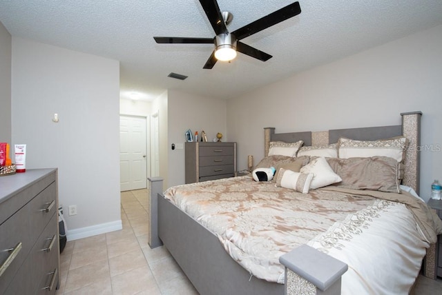 bedroom with a textured ceiling, light tile patterned floors, and ceiling fan