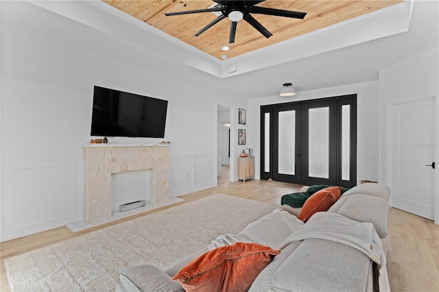 living room with wood ceiling, a tray ceiling, and light wood-type flooring