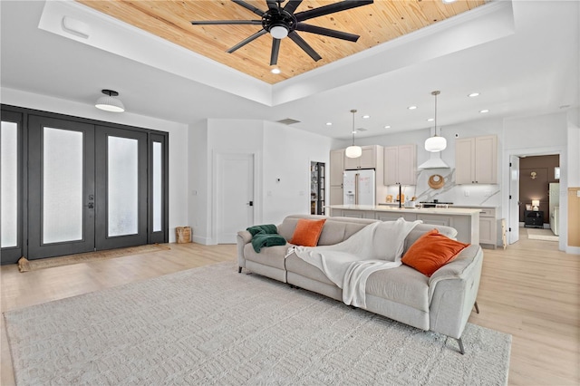 living room featuring french doors, wood ceiling, light wood-type flooring, a raised ceiling, and ceiling fan