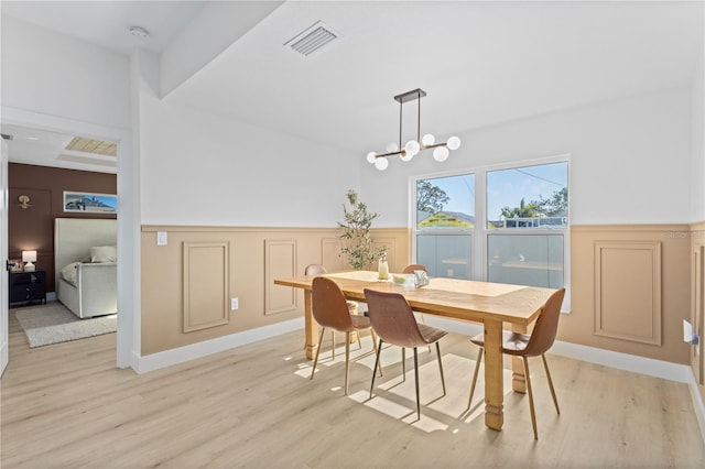 dining area with light hardwood / wood-style flooring and a notable chandelier