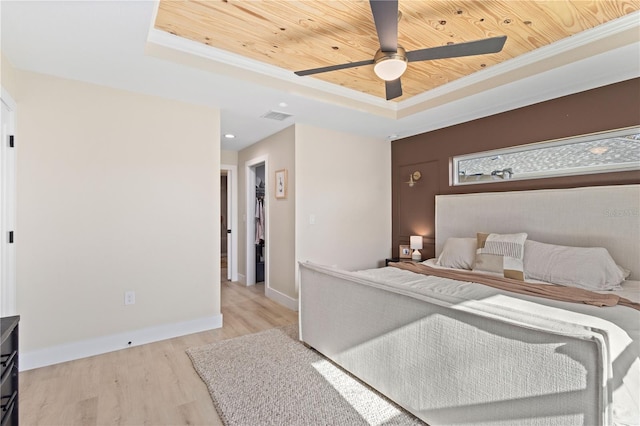 bedroom with wood ceiling, ceiling fan, a tray ceiling, light hardwood / wood-style flooring, and crown molding