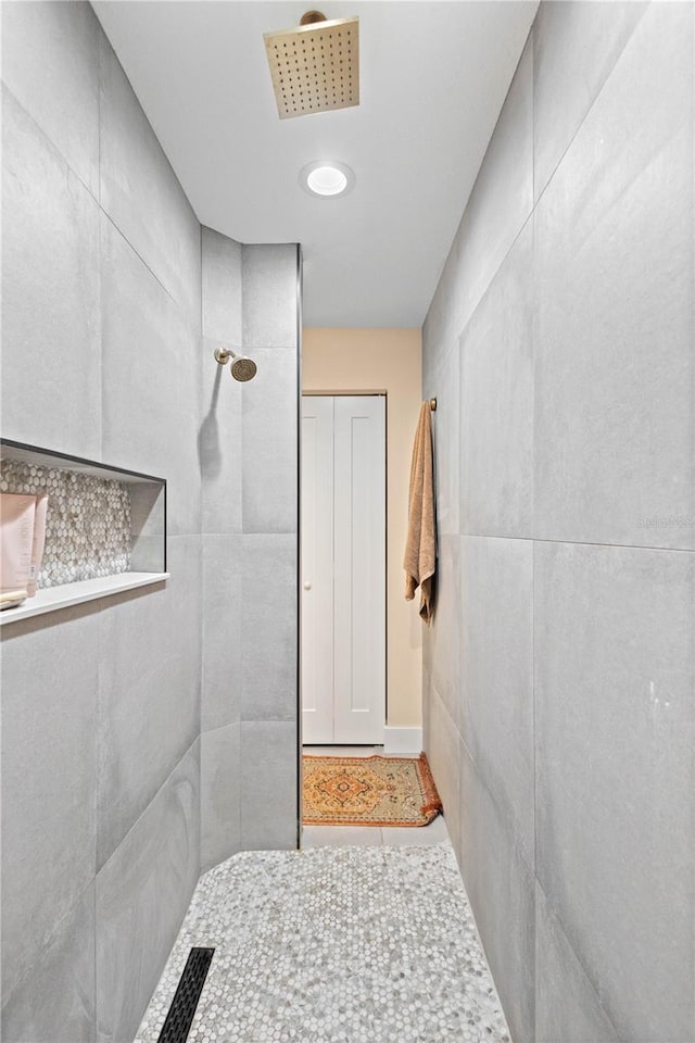 bathroom featuring tile patterned floors, tile walls, and tiled shower