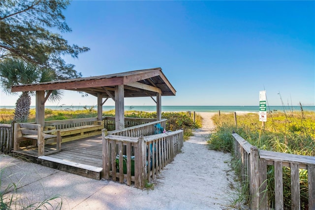 view of home's community with a gazebo, a deck with water view, and a beach view