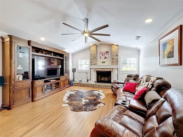 living room featuring lofted ceiling, ornamental molding, a textured ceiling, light hardwood / wood-style floors, and ceiling fan