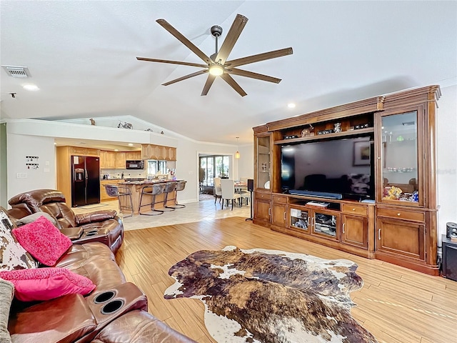 living room featuring vaulted ceiling, light hardwood / wood-style flooring, and ceiling fan